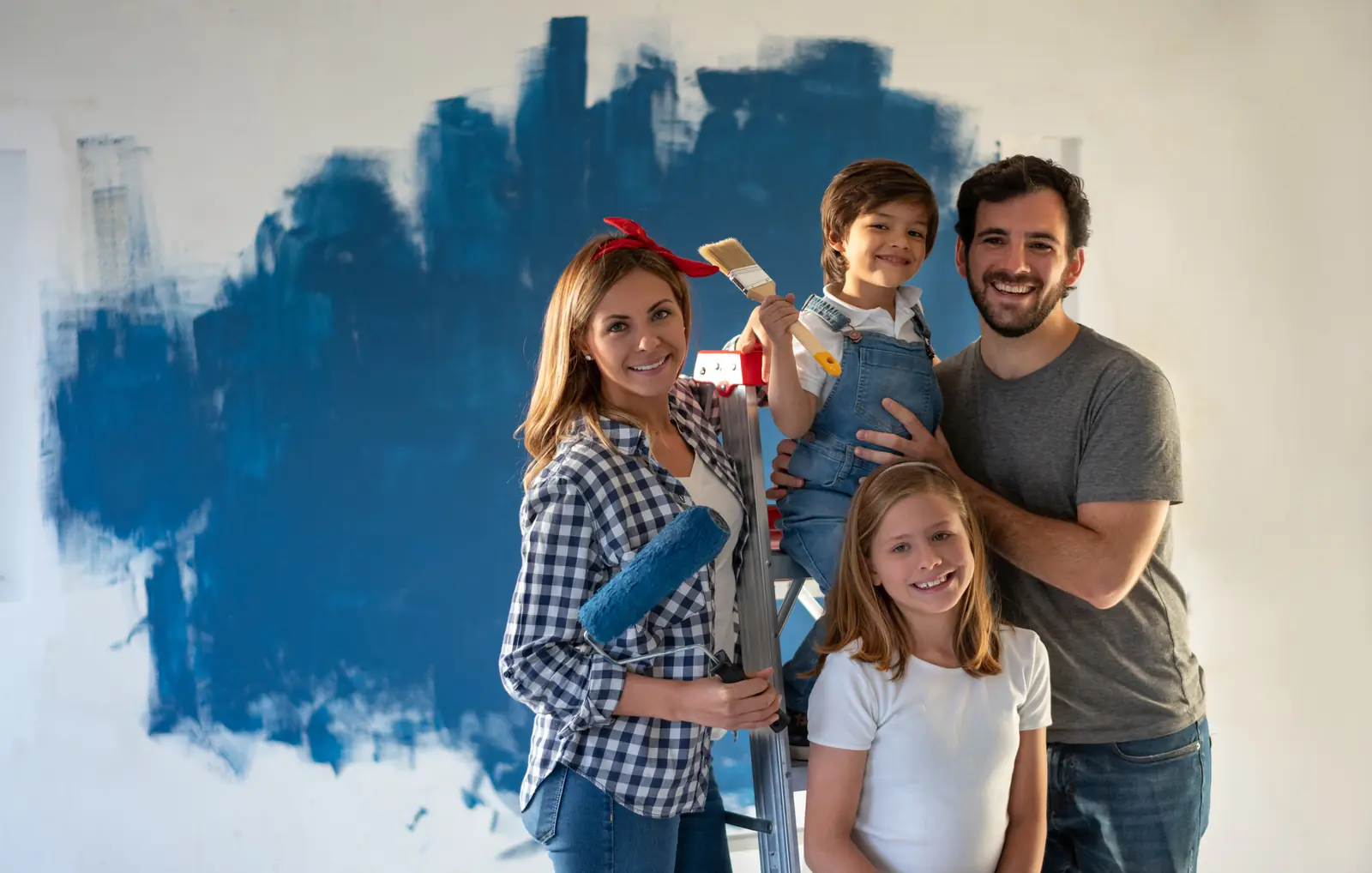 Familia sonriendo frente a la pared que acaba de pintar de azul