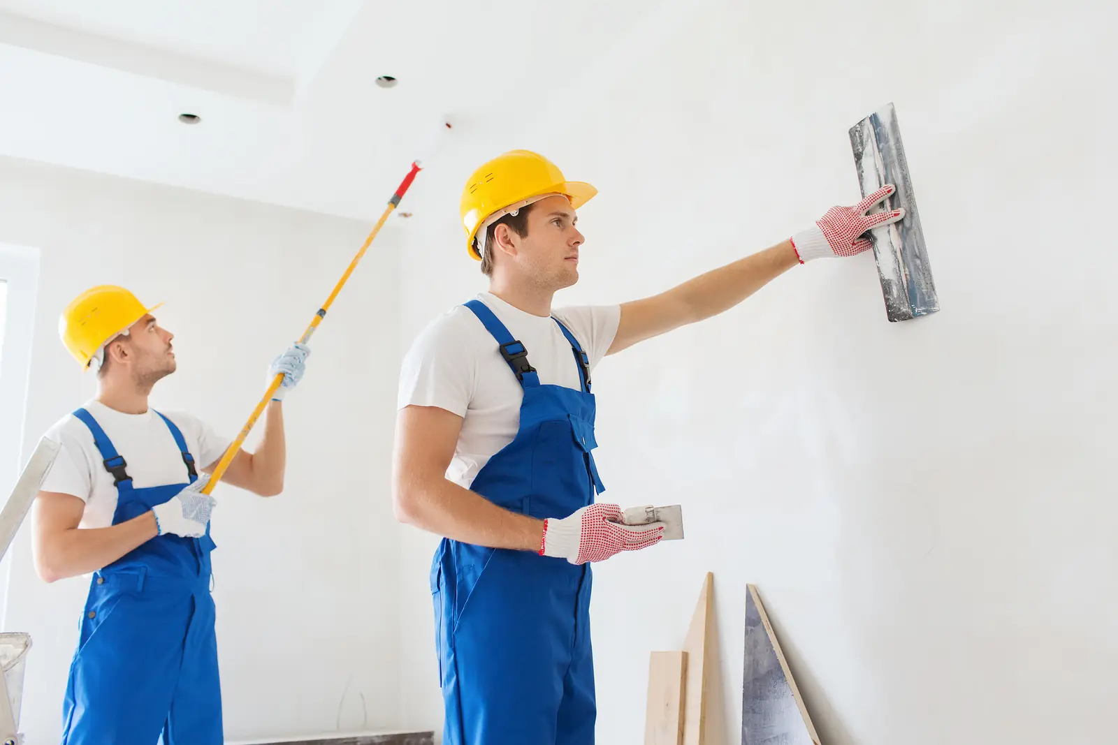 Dos pintores profesionales pintando una pared en obra